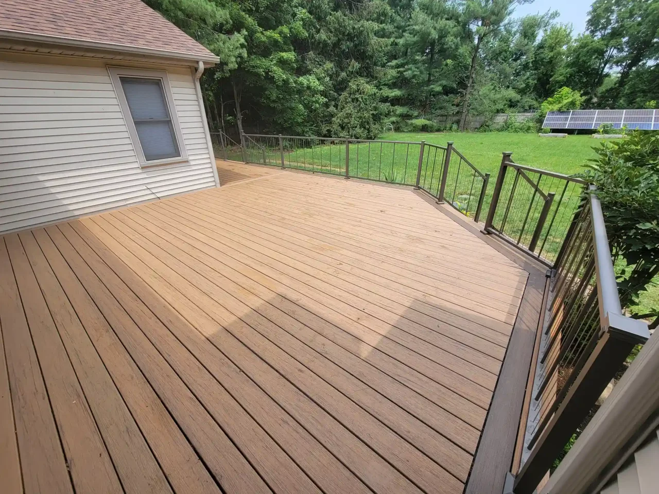 Spacious composite deck with TimberTech Antique Leather decking and black cable railing, overlooking a green backyard.