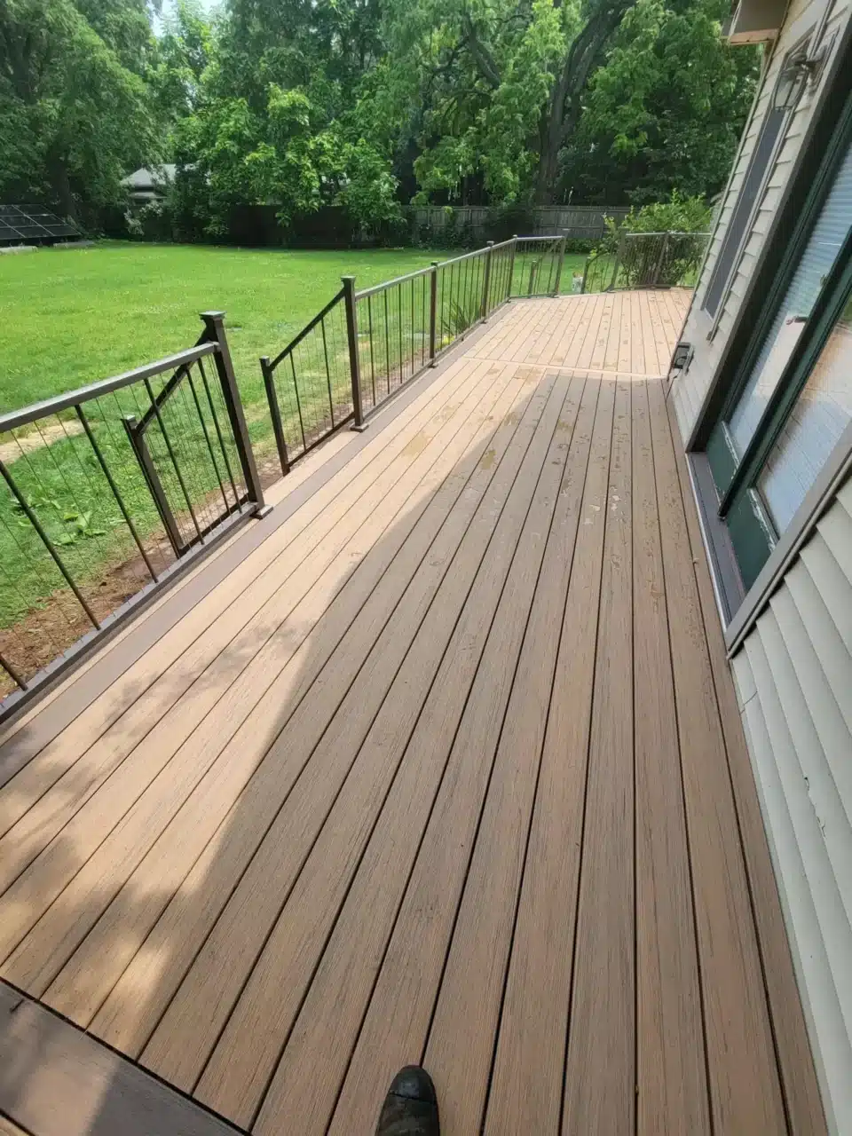 are fire pits safe on composite decks Deck with composite boards, supported by wooden joists and posts, with railing sections in place and open space around it.